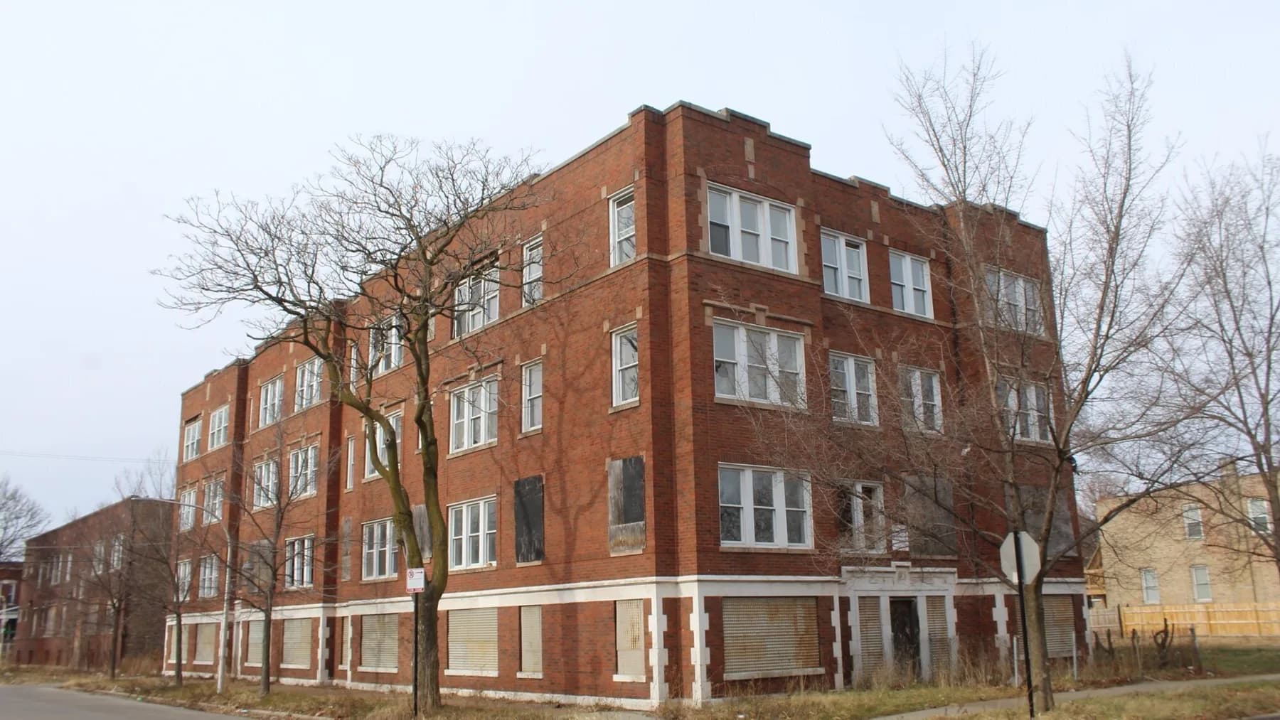 Vacant brick apartment building with bare trees in winter